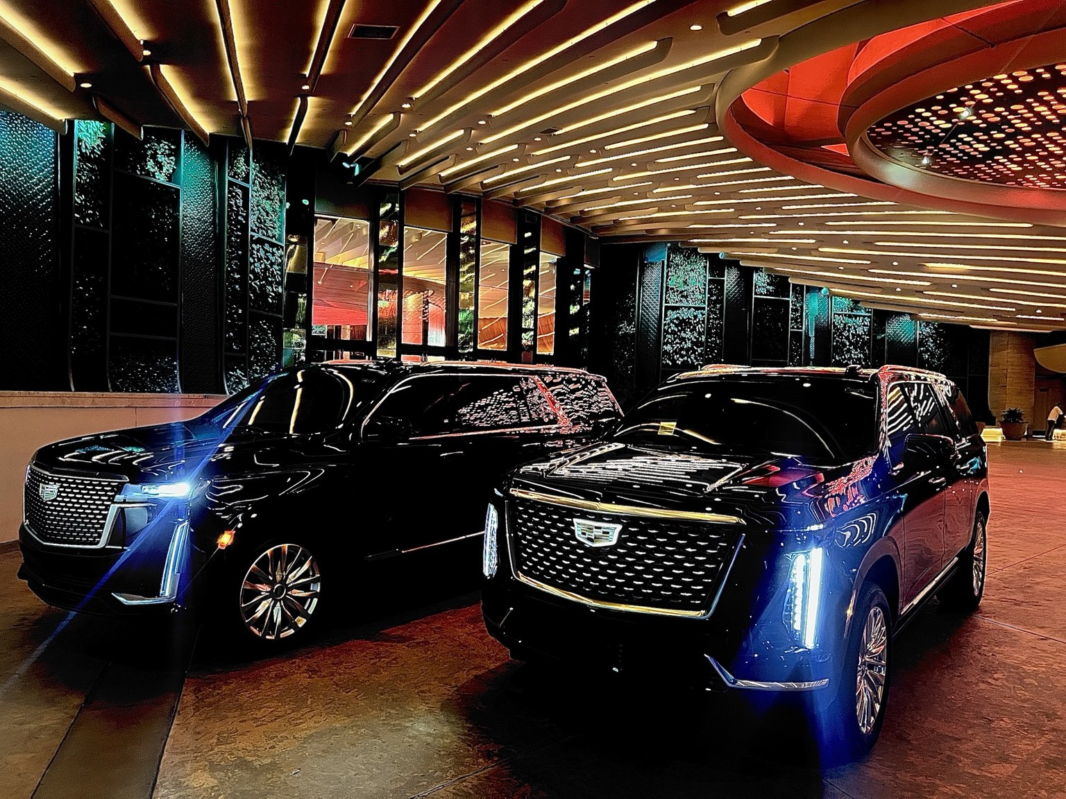 Two black Cadillac Escalades parked at a hotel entrance